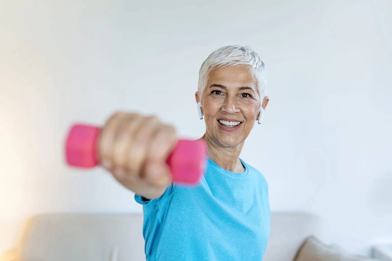 Woman in her fifties doing a strength exercise with dumbbells at home