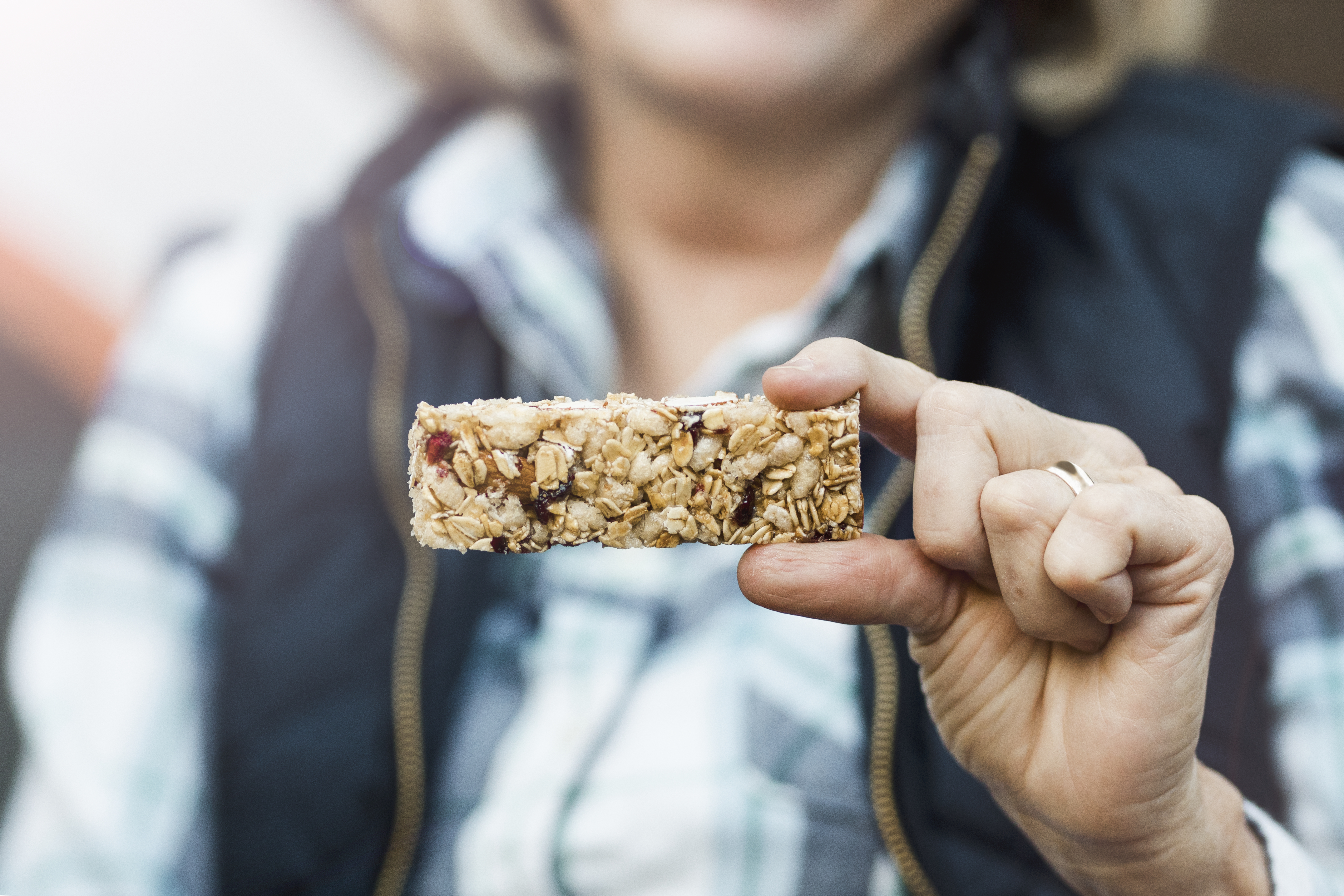 A lady holding a protein bar made with seeds and nuts.