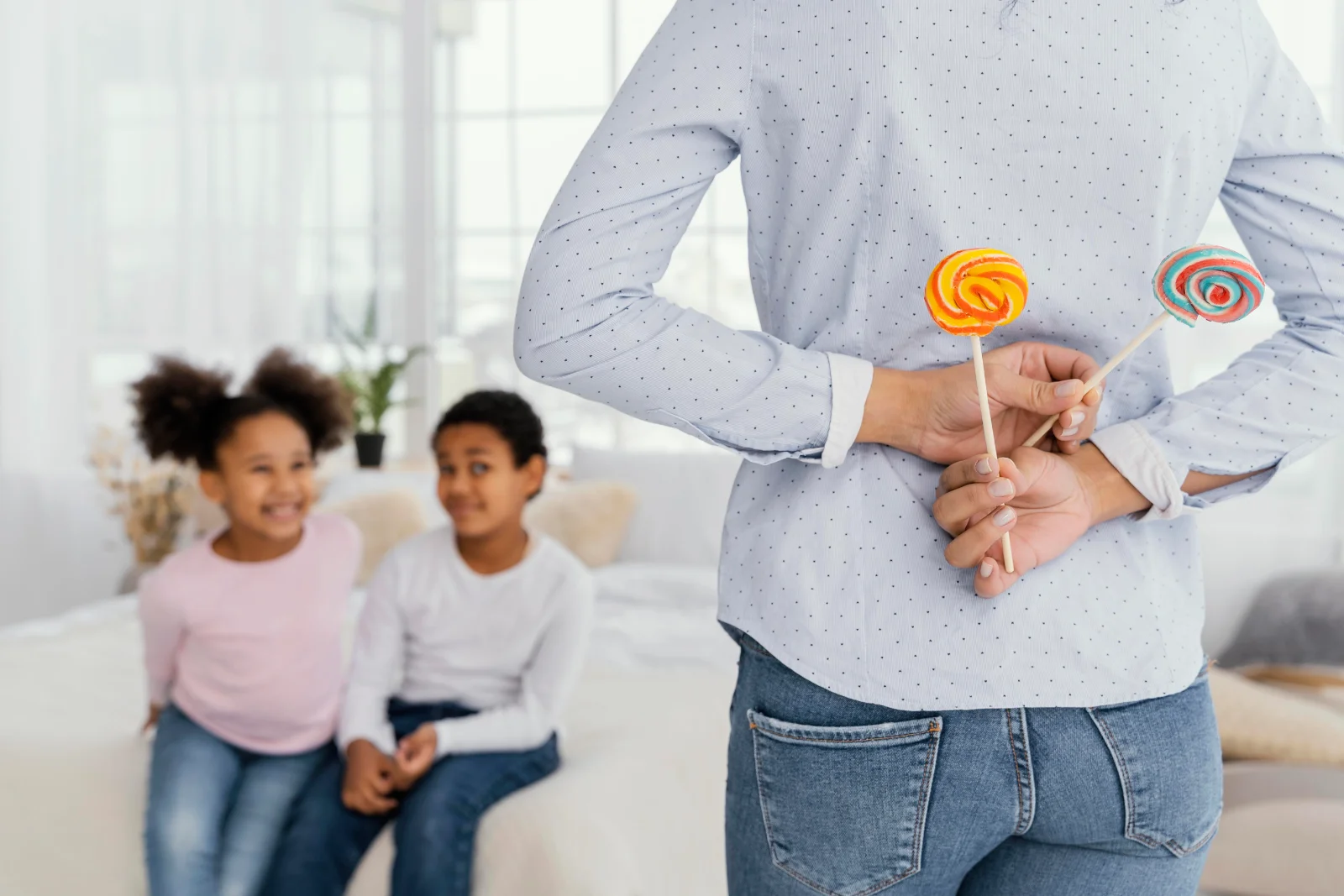 A woman holding candy lollipops behind her back as a treat for her young children that could container E numbers.